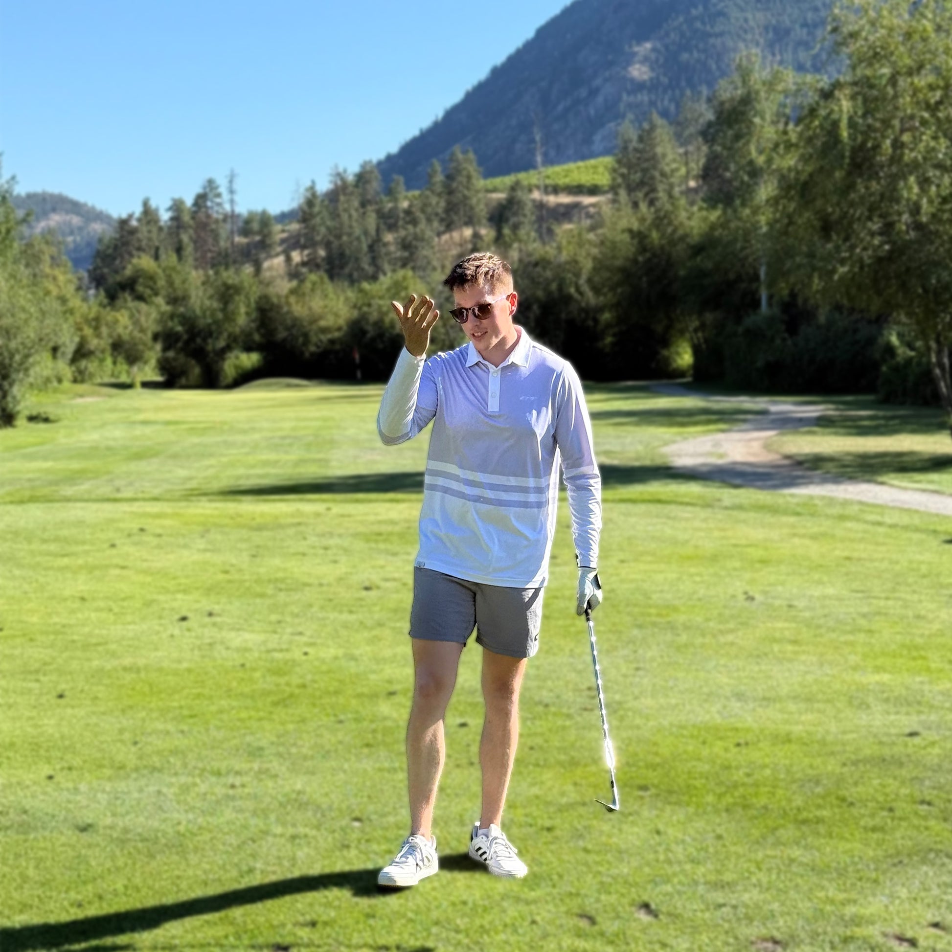 Man on a golf course with mountains and trees in the background wearing a lavender colored UPF 50+ long sleeve golf polo