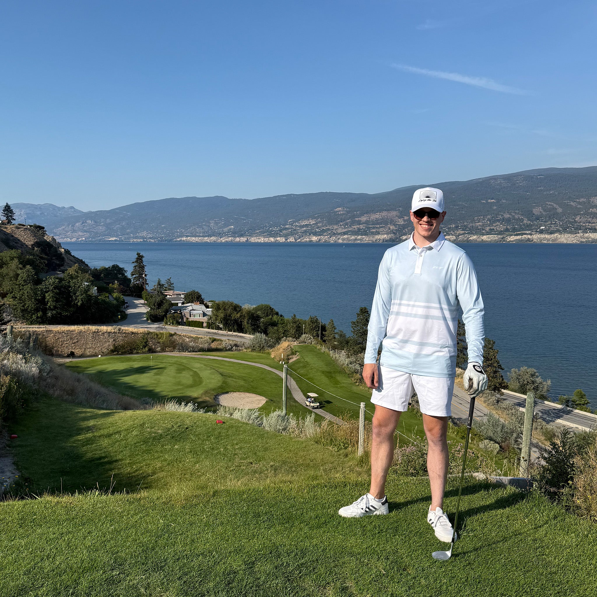 Man on a golf course with a scenic view of water and mountains wearing a powder blue UPF 50+ Long sleeve golf polo.